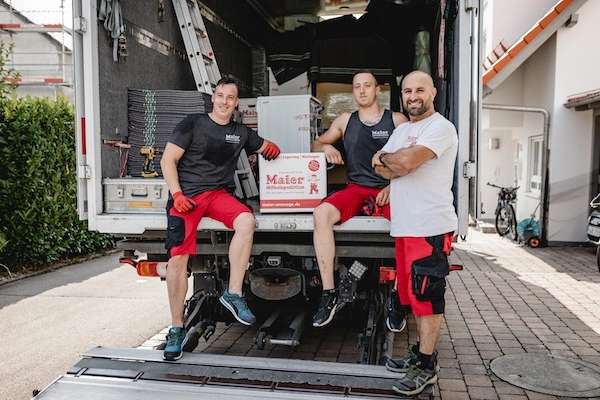 Three removal men with over 40 years of combined experience pose confidently with their removal van near Lake Constance, ready to provide first-class removal services.